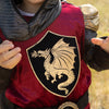 Blason dragon doré sur tunique rouge costume chevalier Tristan