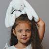 Fillette avec peluche Lapin Méloé blanc 37 cm sur la tête