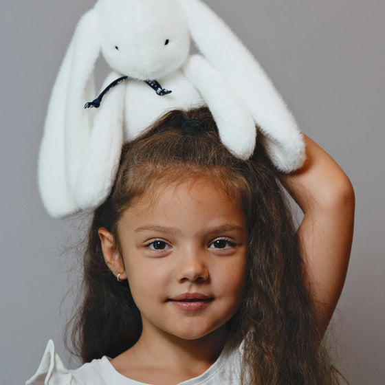 Fillette avec peluche Lapin Méloé blanc 37 cm sur la tête