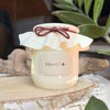 Bougie artisanale avec étiquette "Merci !" et couvercle en tissu crème noué d’un ruban bordeaux – cadeau simple et attentionné