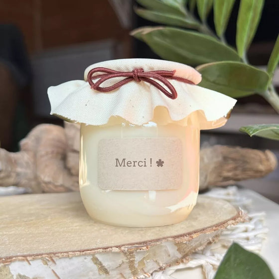 Bougie artisanale avec étiquette "Merci !" et couvercle en tissu crème noué d’un ruban bordeaux – cadeau simple et attentionné