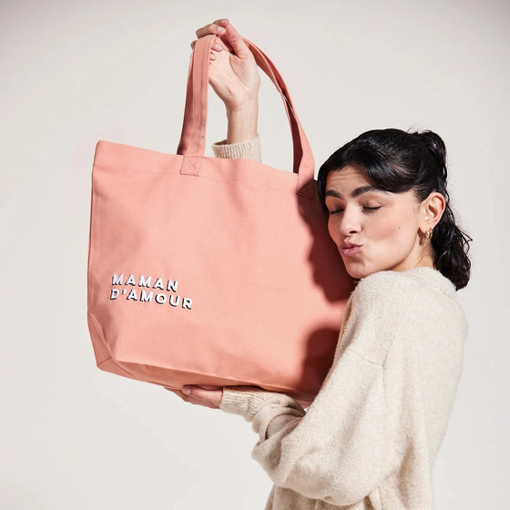 Femme portant un cabas rose saumon avec inscription Maman d’Amour – idée cadeau maman pratique et stylé