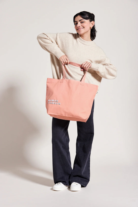 Femme portant un cabas rose saumon avec inscription Maman d’Amour – idée cadeau maman pratique et stylé
