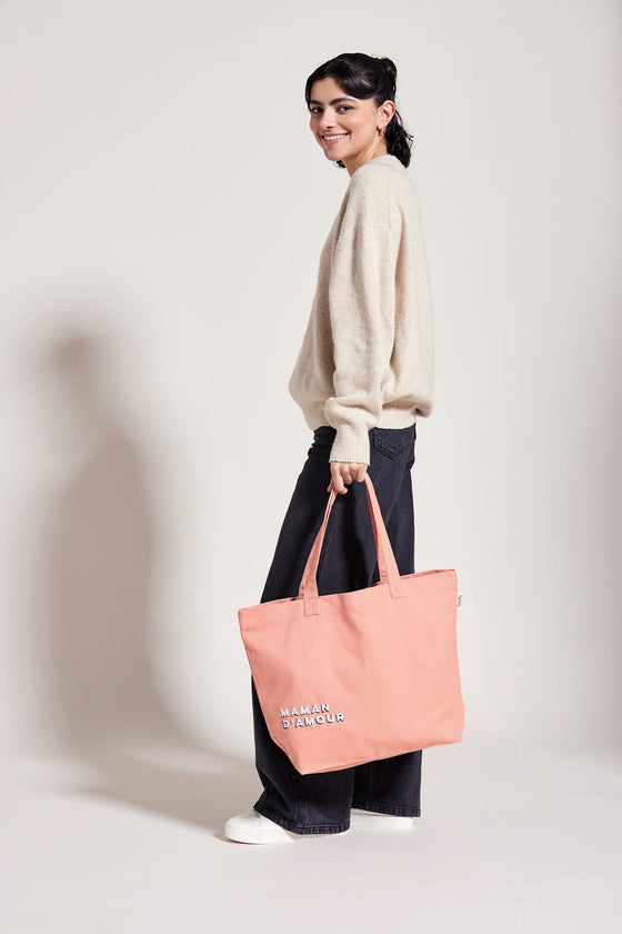 Femme portant un cabas rose saumon avec inscription Maman d’Amour – idée cadeau maman pratique et stylé