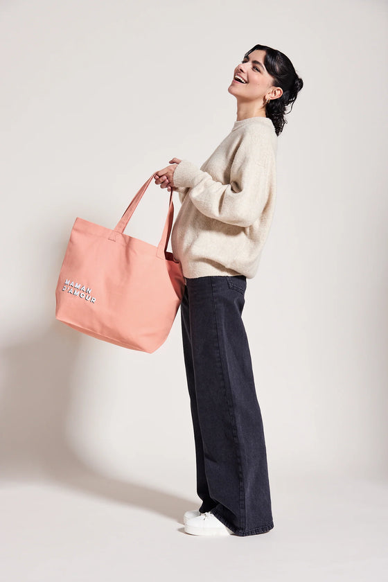 Femme portant un cabas rose saumon avec inscription Maman d’Amour – idée cadeau maman pratique et stylé