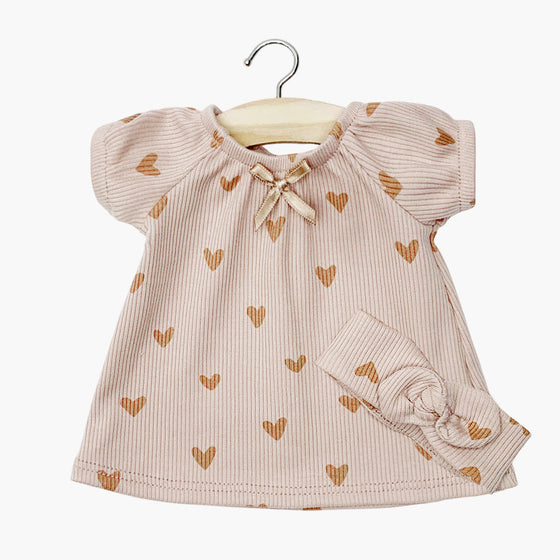 Chemise de nuit "Sabrina" avec headband assorti pour poupée Gordis de Minikane, confectionnée en maille côtelée rose poudré avec imprimé petits cœurs. Modèle à manches courtes avec col froncé et petit nœud décoratif. Accessoire idéal pour habiller un poupon avec douceur et élégance.