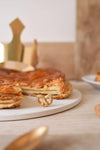 Fève Bretzel Baubels en porcelaine artisanale beige et dorée sur carte Les Jolies Fèves