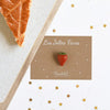Fève Fraise Baubels en porcelaine artisanale rouge brillante sur carte Les Jolies Fèves