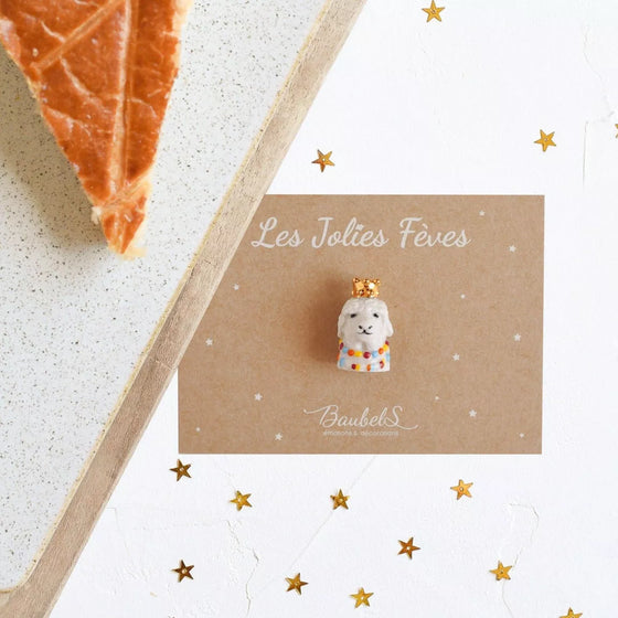 Fève Lama Baubels en porcelaine artisanale avec couronne dorée sur carte Les Jolies Fèves