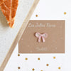 Fève Nœud Rose Baubels en porcelaine artisanale sur carte Les Jolies Fèves