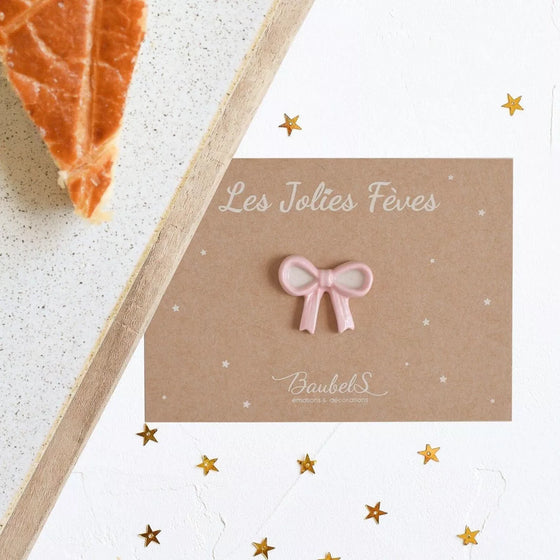 Fève Nœud Rose Baubels en porcelaine artisanale sur carte Les Jolies Fèves