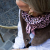 Femme élégante portant un foulard rose imprimé léopard – accessoire mode femme chic