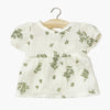 Robe "Faustine" en coton double gaze pour poupée Babies de Minikane, imprimé floral délicat sur fond écru. Modèle à manches courtes bouffantes et coupe évasée, conçu pour habiller un poupon avec élégance. Accessoire idéal pour enrichir la garde-robe des poupées.